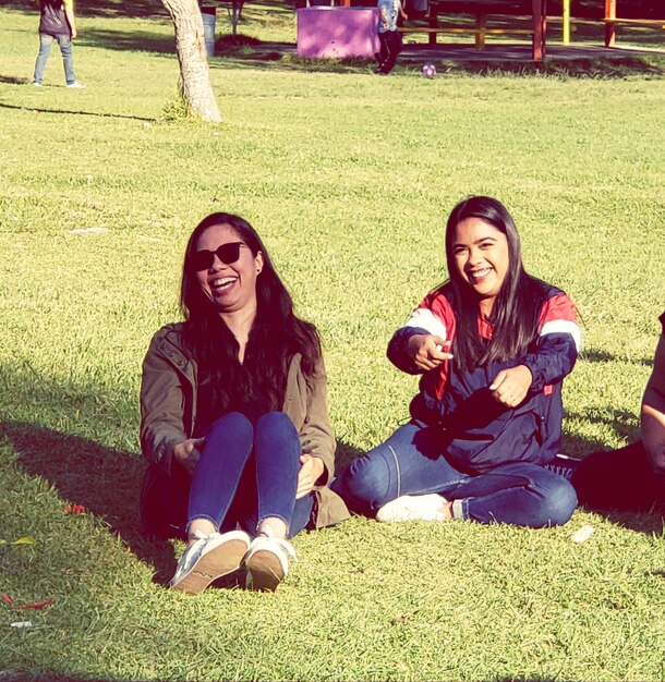 Photo portrait of smiling young women sitting on grass