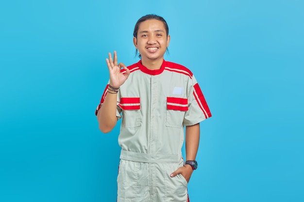 Portrait of smilling handsome man wearing mechanical uniform  showing gesturing okay sign