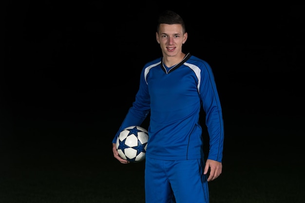 Portrait Of A Soccer Player And Ball On Football Stadium Field Isolated On Black Background