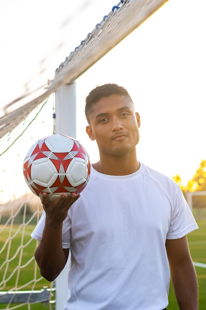 Photo portrait of soccer player holding the ball outdoors young man player holding a soccer ball on the playing field