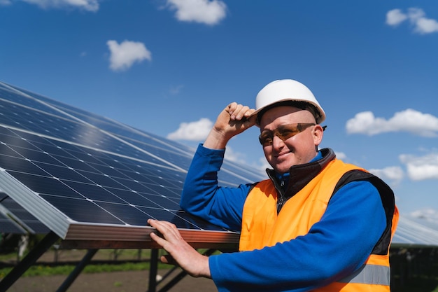 Portrait of a solar farm worker leaning against the panels