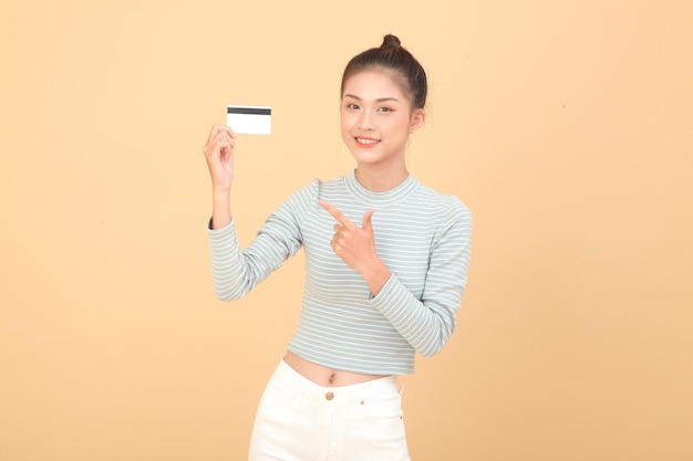 Portrait of South East Asian young beautiful cheerful lady hold bank credit or debit card isolated on background