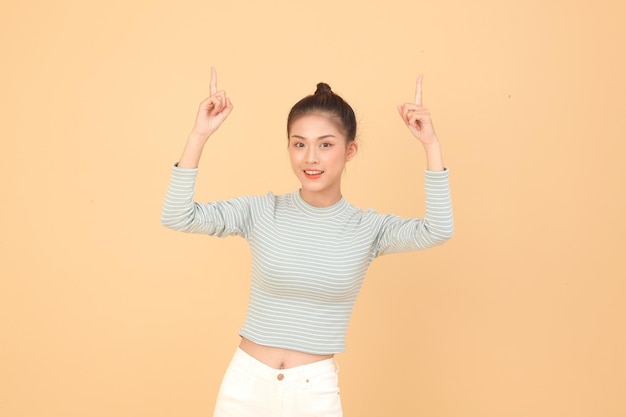 Portrait of South East Asian young beautiful cheerful lady with hand gesture pointing something isolated on background