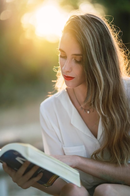 Portrait of a Spanish woman with hair highlights reading a book in a park on a sunny day