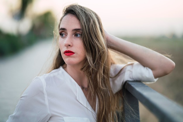 Portrait of a Spanish woman with long highlighted hair leaning on a pavement fence