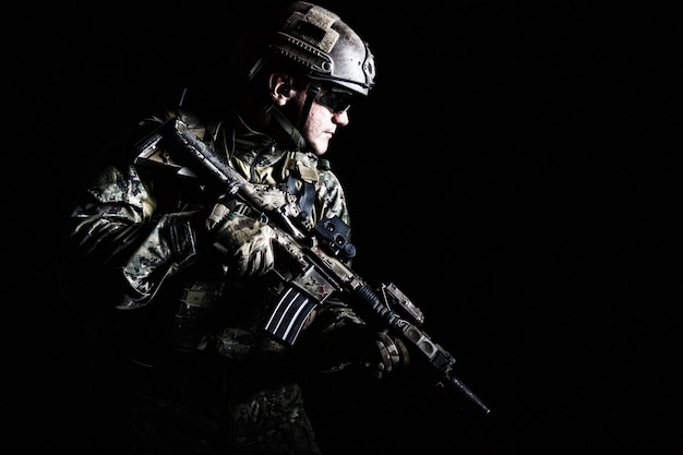 Photo portrait of special forces soldier in field uniforms with weapons, portrait on black