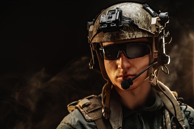 Photo portrait of special forces soldier in helmet and glasses in the dark