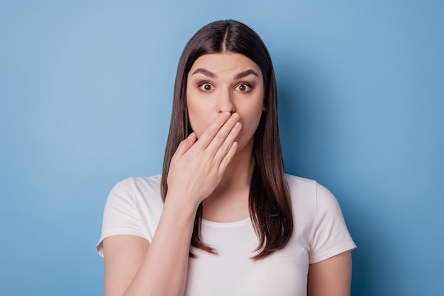 Portrait of speechless staring crazy lady palm cover mouth look camera on blue background