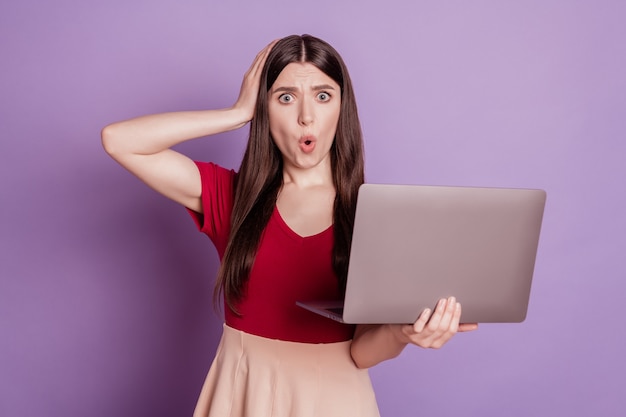 Portrait of speechless troubled lady hold laptop hand head open mouth crazy face on purple background