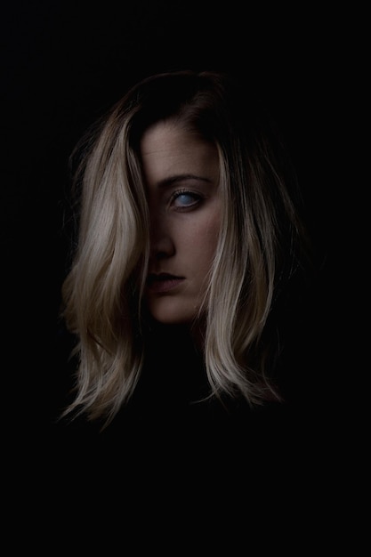 Photo portrait of spooky young woman against black background