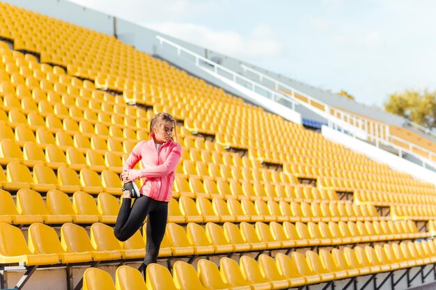 Портрет спортивной женщины, делающей разминку на стадионе