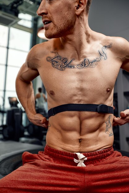 Photo portrait of sportsman checking heart rate on fitness trekker after training in gym