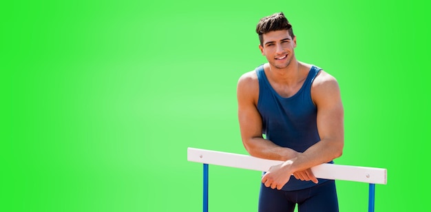 Portrait of sportsman is smiling and posing on a hurdle