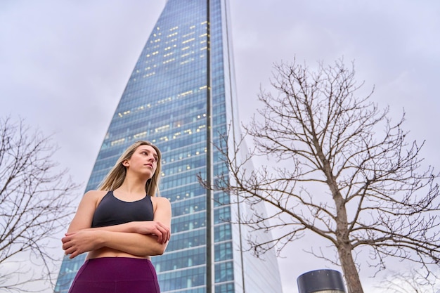 Portrait of a sportswoman in the city with her arms crossed on a background of skyscrapers