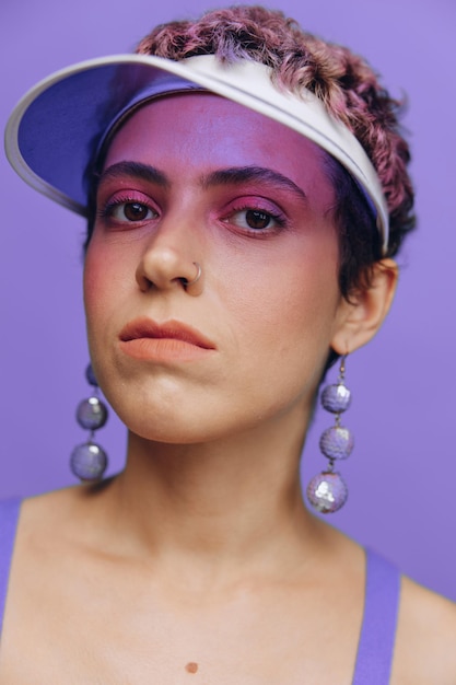 Portrait of a sporty fashion woman posing in a purple sports suit for yoga and a transparent cap on a purple background monochrome high quality photo