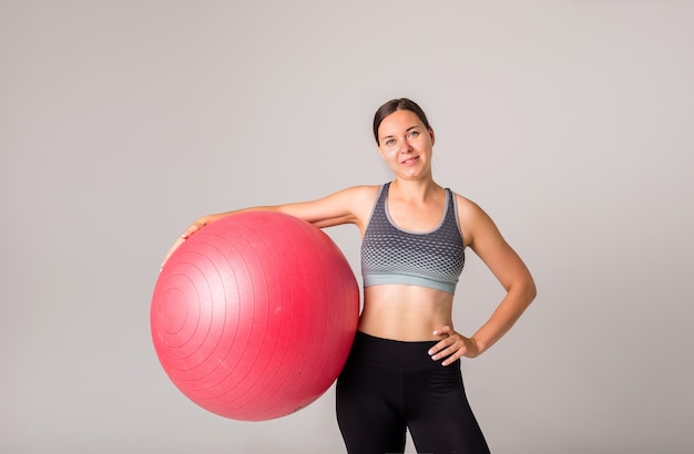 Портрет спортивной девушки с фитнес-мячом на белом с копией пространства