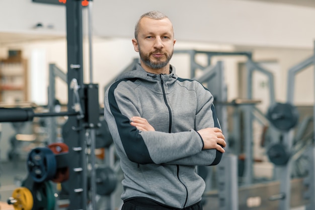 Portrait of sporty man with folded hands in the gym