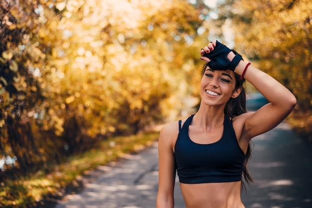 Портрет sporty женщины в парке имея паузу.