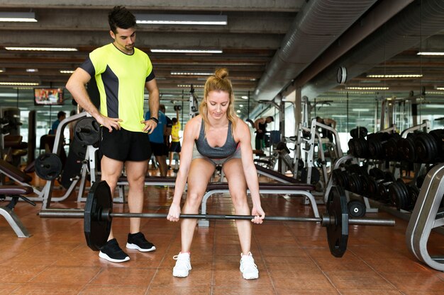 Portrait of sporty young couple doing muscular exercise in gym.