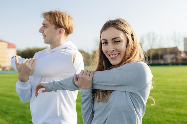 屋外でトレーニングするスポーティな若いカップルの肖像画