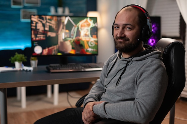 Ritratto di streamer che si prepara a giocare ai videogiochi sul computer. giocatore con le cuffie che si prepara a trasmettere in streaming il gioco dal vivo, giocando con tastiera e mousepad sul monitor. streaming del giocatore