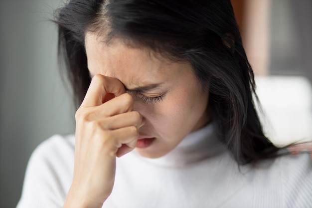 Portrait of stressed sick asian woman with headache depressed woman suffers from vertigo dizziness migraine hangover overwork office syndrome depicting health care and mental health concept