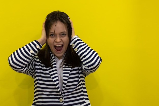 Photo portrait of a stressed young businesswoman screaming with hands on head on yellow background