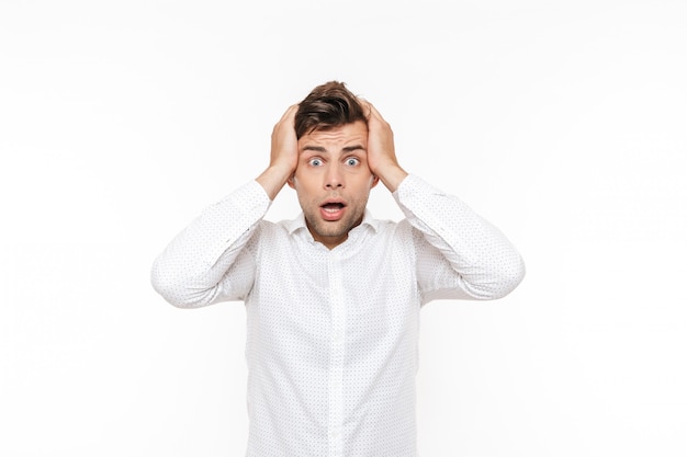 Portrait of stressed young man grabbing his head and expressing problem.