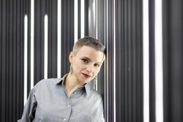 Portrait of a strong caucasian adult woman against the background of a wall with vertical lamps