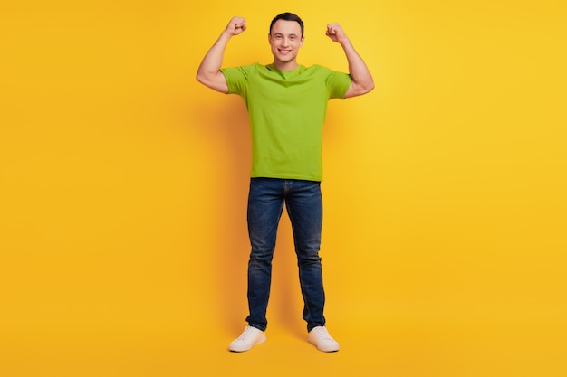 Portrait of strong cool guy show two hands muscle on yellow background