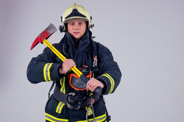 Портрет сильного пожарного в огнеупорной форме на белом фоне студии