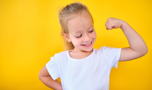Portrait strong power preschool little girl flexing arm muscle smile isolated