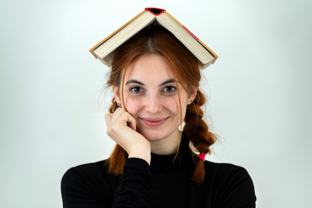 Portrait of a student girl with an open book on her head