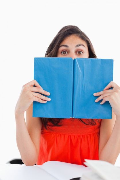 Portrait of a student hiding behind a blue book