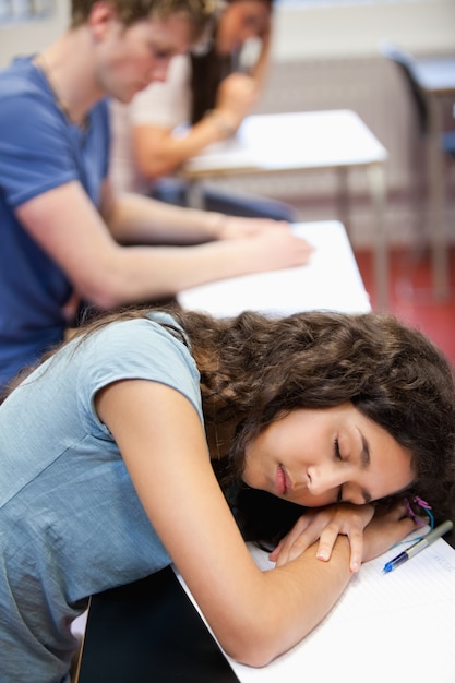 彼女の机の上で眠っている学生の肖像