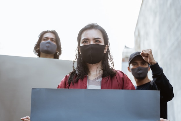 Portrait students holding blank paper conducting demonstrations by following health protocols