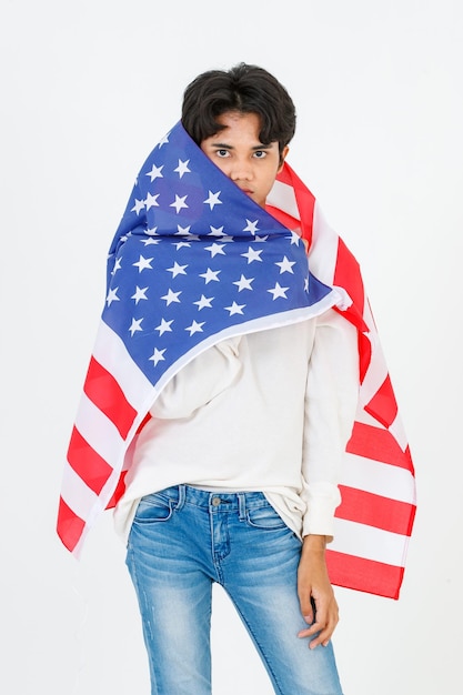 Portrait studio shot Asian young LGBT gay bisexual homosexual male fashionable model in casual outfit standing holding using United states of America USA national flag cover body on white background