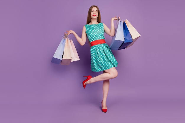 Portrait of stunning lady hold many shop bags posing wear mini dress high-heels on violet background