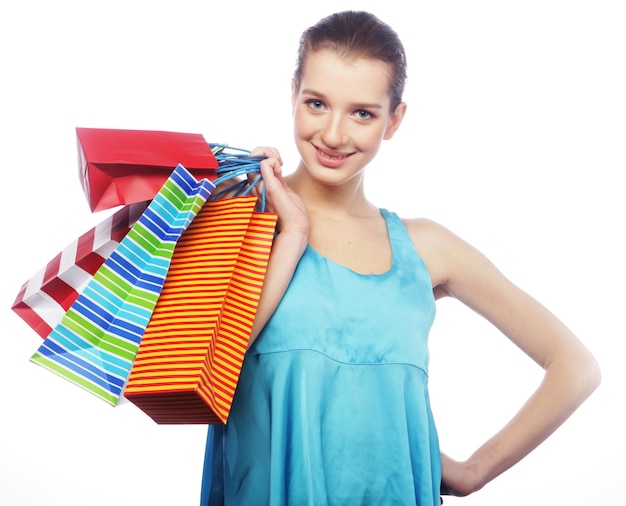 Portrait of stunning young woman carrying shopping bags on white