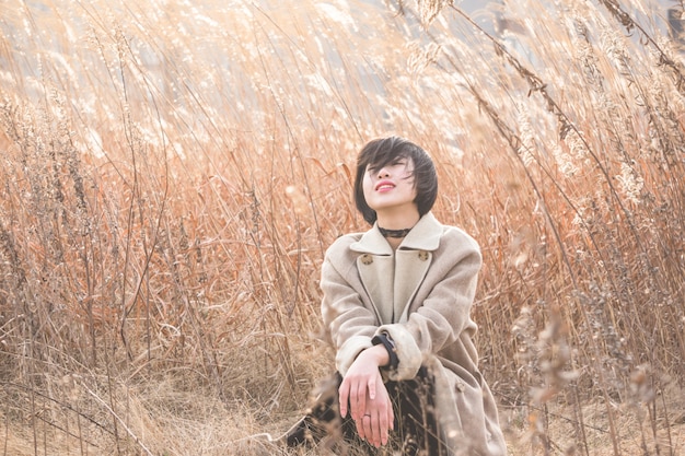 portrait of style woman sitting amidst reed field