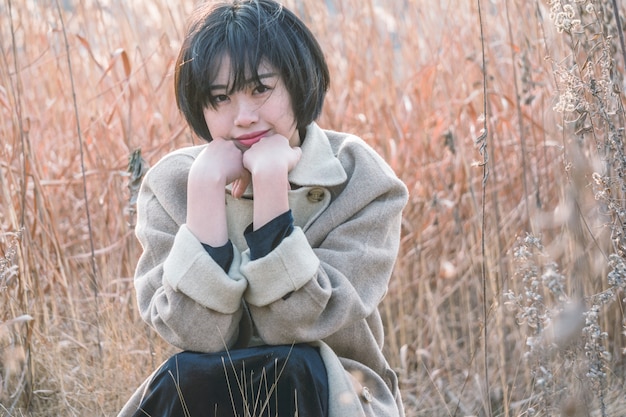 portrait of style woman sitting amidst reed field