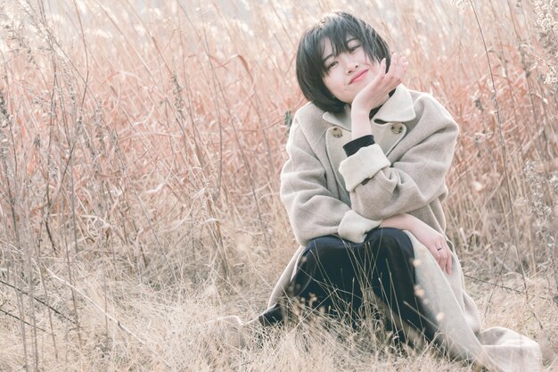 portrait of style woman sitting amidst reed field