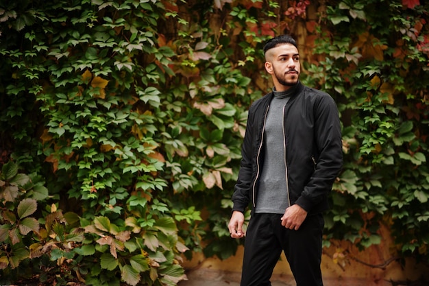 Portrait of stylish arab beard man wear grey turtleneck and black jaket Arabian model guy on a background of autumn leaves