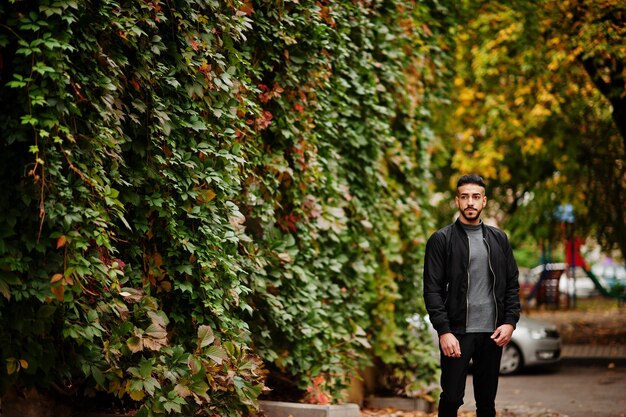 Portrait of stylish arab beard man wear grey turtleneck and black jaket Arabian model guy on a background of autumn leaves