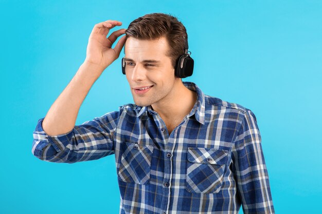 Portrait of stylish attractive handsome young man listening to music on wireless headphones having fun modern style happy emotional mood 