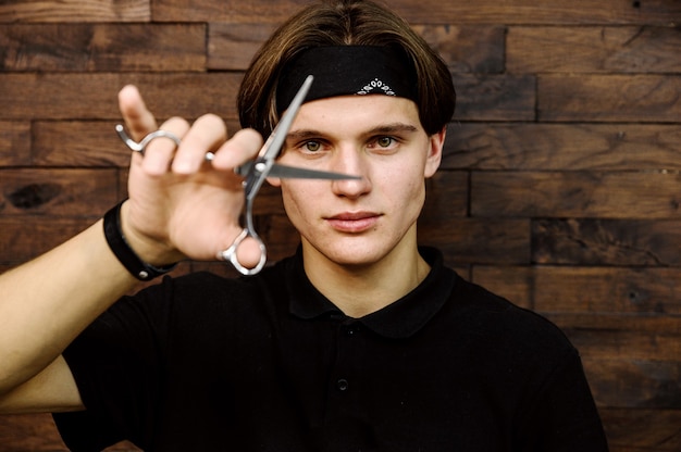 Portrait of stylish barbershop master on dark wooden background