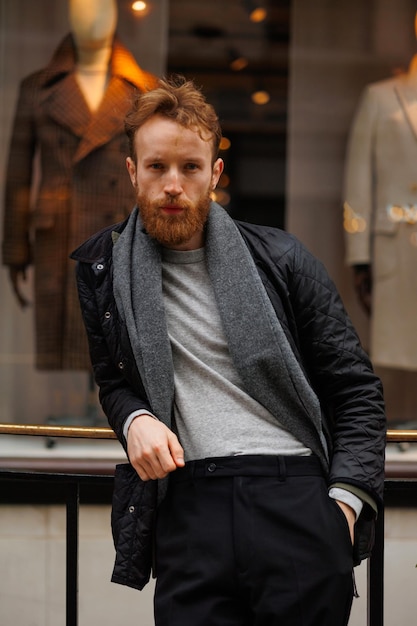 Portrait of a stylish bearded man against the background of elegant clothing store window