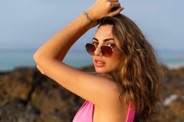 Portrait of a stylish beautiful sensual young woman on a tropical beach at sunset posing