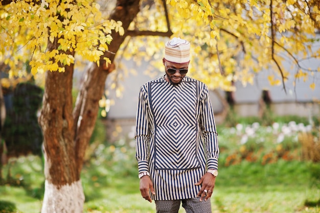 Portrait of stylish black african american man at hat and sunglasses against sunny autumn fall background Rich people in africa at traditional dress