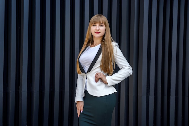 Portrait of stylish business woman near grey wall background